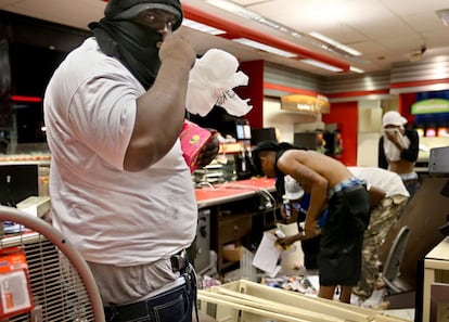 Un saqueador armado con una pistola en la cintura roba artículos de una tienda durante los disturbios en Ferguson (EE UU), el 10 de agosto de 2014.