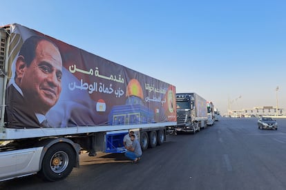 A convoy of trucks loaded with humanitarian aid, one of them with a photo of Egyptian President Abdel Fattah El-Sisi, wait to cross into Gaza. 