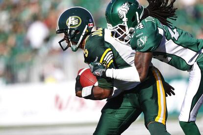 Edmonton Eskimos, de los Edmonton Eskimos es bloqueado por Woodny Turenne, de los saskatchewan Roughriders, en la CFL estadounidense. 