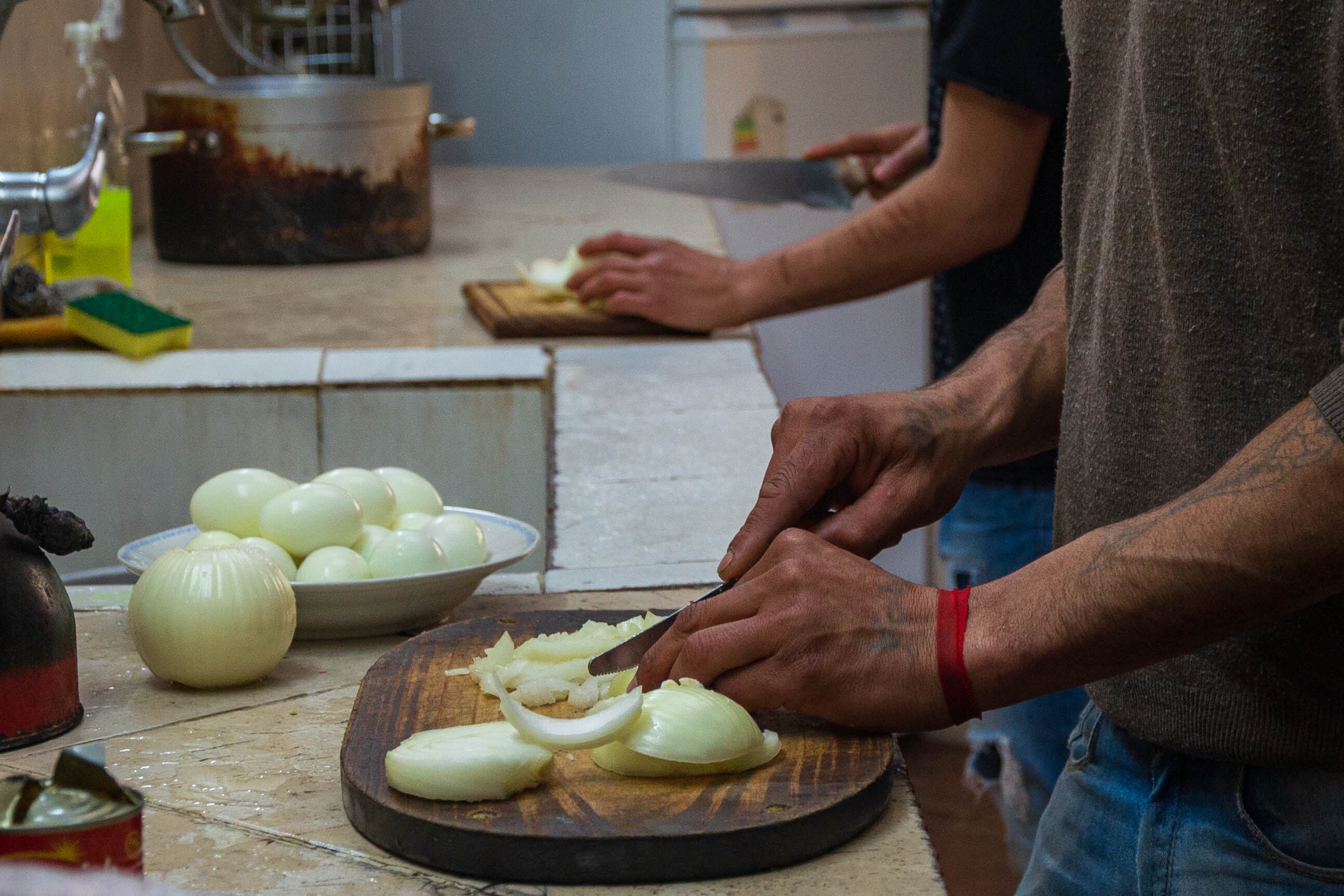 Una persona liberada corta cebollas en una capacitación de cocina, en Montevideo.