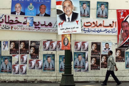 Un hombre camina por una calle de El Cairo repleta de carteles electorales.