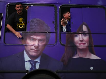 Dos seguidores de Milei celebran el triunfo del candidato ultra, a bordo de un autobús con su rostro estampado a un costado, en Buenos Aires, el 19 de noviembre.