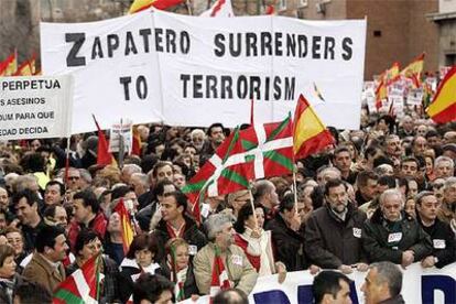 Mariano Rajoy porta la segunda pancarta. Detrás, en inglés, se lee "Zapatero se rinde al terrorismo".