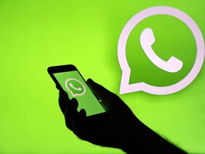 Foto ilustración del logo de WhatsApp en la pantalla de un iPhone enfrente de una televisión.