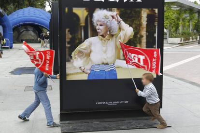 Unos niños juegan con banderas sindicales junto a una fotografía de la duquesa de Alba, exhibida en una exposición en la calle, cerca del lugar de la concentración