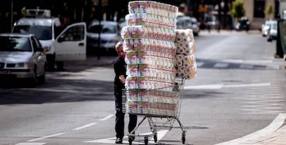 Un reponedor lleva un carro con papel higiénico a un comercio en Málaga.