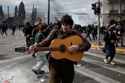 Un hombre toca la guitarra durante las cargas entre manifestantes y policía frente al Palamento.