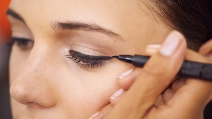 Una maquilladora pinta una raya de eyeliner sobre el párpado de una modelo