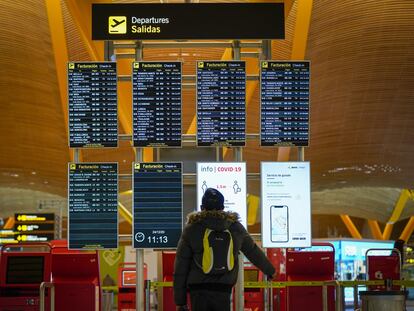 Un pasajero en el panel de salidas del aeropuerto de Barajas (Madrid), en diciembre.