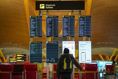 Un pasajero en el panel de salidas del aeropuerto de Barajas (Madrid), en diciembre.