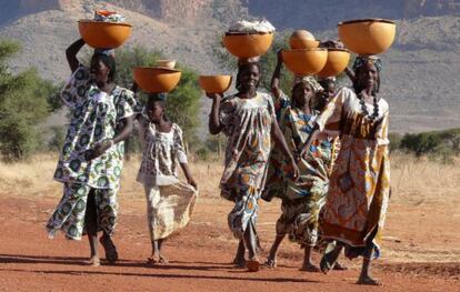 Mujeres de la tribu peul en Mali portan sobre sus cabezas grandes cuencos con ropa y leche.