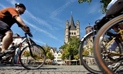Unos ciclistas pasan cerca de la iglesia de San Martin en Colonia (Alemania)