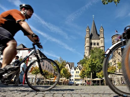 Unos ciclistas pasan cerca de la iglesia de San Martin en Colonia (Alemania) 