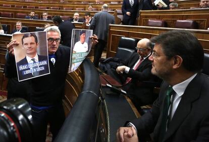 Diego Ca&ntilde;amero se acerca al esca&ntilde;o del ministro de Justicia, Rafael Catal&aacute;, con unas fotograf&iacute;as de I&ntilde;aki Urdangar&iacute;n y Andr&eacute;s Bodalo, durante una sesi&oacute;n en el Congreso. 