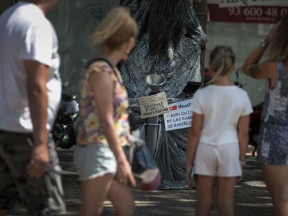 Turistas en las Ramblas ante una estatua humana.