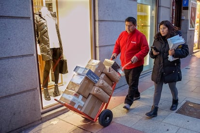 El repartidor Amado López y su mujer Mónica se dirigen cargados de paquetes a la furgoneta de reparto en Madrid.