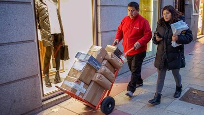El repartidor Amado López y su mujer Mónica se dirigen cargados de paquetes a la furgoneta de reparto en Madrid.