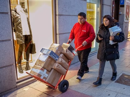 El repartidor Amado López y su mujer Mónica se dirigen cargados de paquetes a la furgoneta de reparto en Madrid.