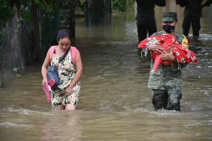 Una mujer es auxiliada en las inundaciones en Nacajuca, en Tabasco (México), por un elemento del Ejército que carga a su bebe el pasado domingo.
