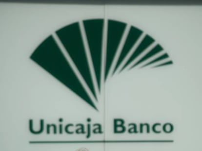 Una mujer pasa por delante de una oficina de Unicaja Banco. 