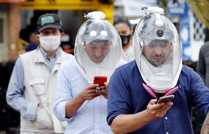 El ingeniero aeronáutico Andrés Felipe Giraldo (derecha) y el diseñador industrial Ricardo Andrés Conde (centro), utilizan la burbuja que han desarrollado para evitar el coronavirus en la ciudad de Bogotá (Colombia). El país ha superado este lunes los 250.000 casos de coronavirus tras confirmar más de 8.000 adicionales, según el último balance publicado por el Ministerio de Salud del país.