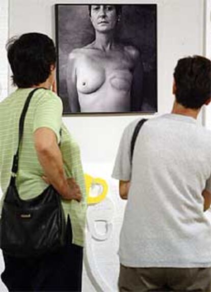 Dos mujeres visitan una exposición de fotos de mujeres con los pechos amputados por cáncer de mama.