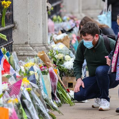 Un padre con sus hijas observa los ramos de flores frente al palacio de Buckingham en Londres, este sábado.