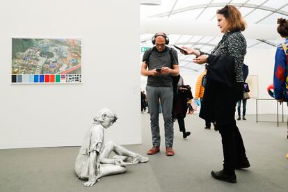 Una mujer saca una fotografía de una escultura en Art Basel París
