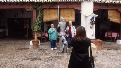 Turistas fotografiándose junto a una estatua de Don Quijote en el pozo de la Venta del Quijote, en Puerto Lápice.