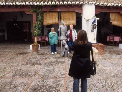 Turistas fotografiándose junto a una estatua de Don Quijote en el pozo de la Venta del Quijote, en Puerto Lápice.