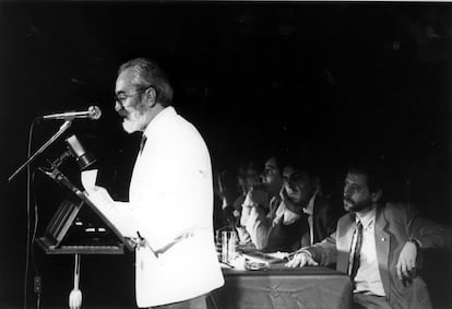 El poeta Ángel González lee sus poemas en el patio principal del Palacio Real de Madrid, en una velada poética organizada por Patrimonio Nacional, el 9 de junio de 1990. Detrás, Juan Carlos Suñén, Ángel Rupérrez y Luis García Montero. El acto se convirtió en un homenaje a Carlos Barral y Jaime Gil de Biedma, recientemente fallecidos.