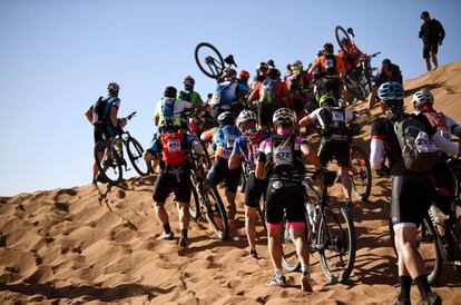 Competidores suben a pie una duna durante la Etapa 4 de la 13ª edición de la carrera de ciclismo de montaña Titan Desert 2018 entre Boumalne Dades y Merzouga, el 2 de mayo de 2018.