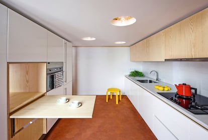 La cocina, con carpintería de pino y lacada en blanco, tiene una campana Pando, placas de gas y horno Smeg, frigorífico Liebherr y lavavajillas Miele. Las luces son el modelo Teti de Vico Magistretti para Artemide.