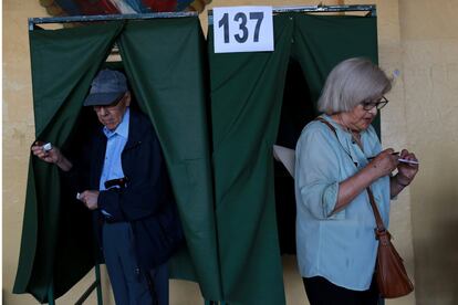 Varios votantes eligen las papeletas de sus candidatos antes de votar, en un centro electoral de Chile.