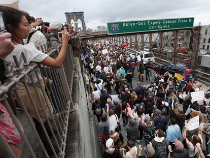 Un grupo de personas fotografía y anima a los manifestantes de Ocupa Wall Street, el sábado en el puente de Brooklyn.