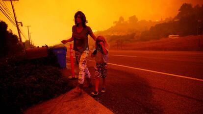 Una madre y su hija huyen de las llamas en California. / REUTERS