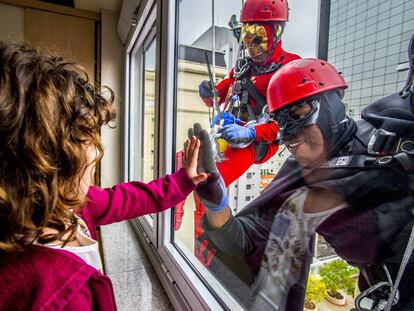 Hombres disfrazados de Batman y de Flashgordon limpian los cristales antes de ir a visitar a los niños enfermos (Sao Paulo, Brasil).  
 