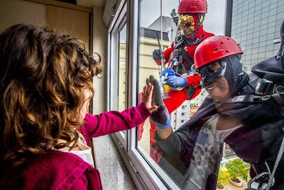 Hombres disfrazados de Batman y de Flashgordon limpian los cristales antes de ir a visitar a los niños enfermos (Sao Paulo, Brasil).  
 