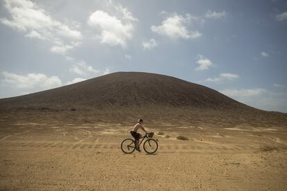 Un chico pasa en bicicleta por las cercanías de uno de los cráteres de volcán de La Graciosa, en el Parque Natural del archipiélago de Chinijos.