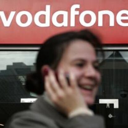 Mujer habla por teléfono delante de una tienda de Vodafone