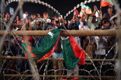 Una bandera del partido paquistaní Tehreek-e-Insaf vista a través de un alambre de púas cuelga de una valla, durante una reunión de la campaña electoral antes de las elecciones generales en Lahore. 