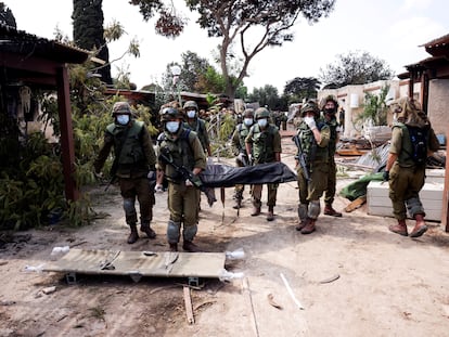 Unos soldados israelíes trasladaban el martes a una víctima de la matanza perpetrada por Hamás en el kibutz Kfar Aza.