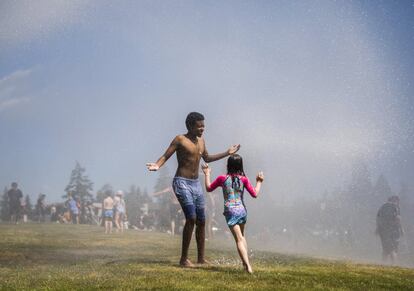 Quienes tienen cerca un parque han acudido a refrescarse con los aspersores de agua. En la imagen, Yefikir Getahun, de 13 años, se deja mojar por una de las mangueras instaladas por el departamento de bomberos de Everett, en Washington, el 26 de junio.