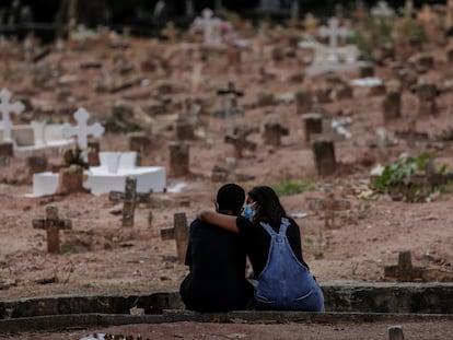 Familiares de vítima de covid-19, sepultada no Rio de Janeiro, se apoiam em cemitério em imagem de abril de 2021