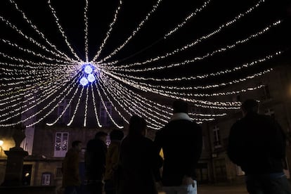 Unos jóvenes pasean por la Praza do Toural, en Santiago de Compostela, donde se encuentra la casa natal de Mariano Rajoy, bajo una iluminación navideña.