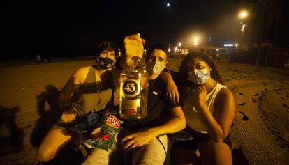 Joves fent un 'botellón' a la platja de la Barceloneta, divendres a la nit.