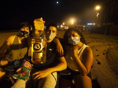 Joves fent un 'botellón' a la platja de la Barceloneta, divendres a la nit.