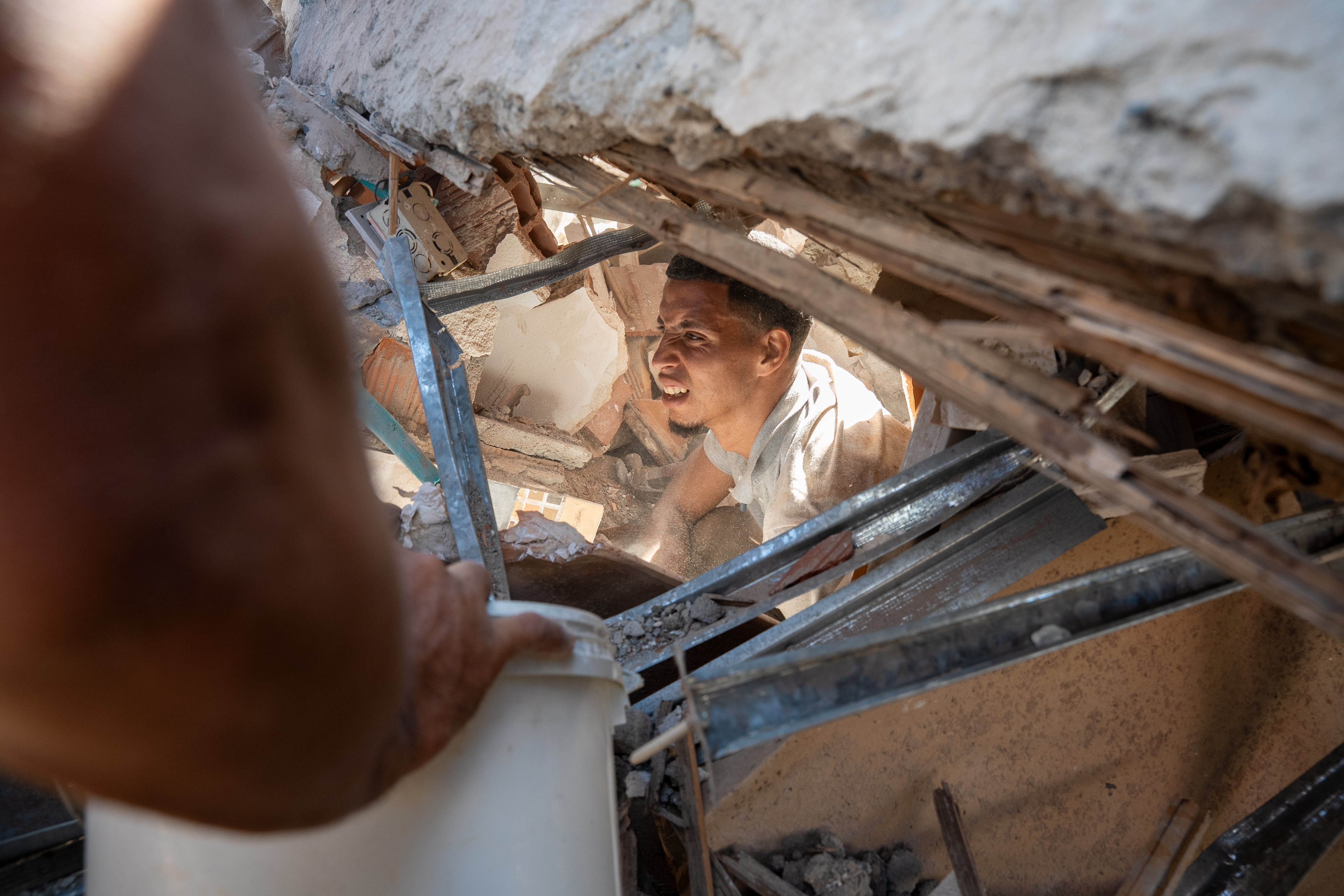 Un hombre busca sobrevivientes bajo los escombros de un edificio, en Cali.