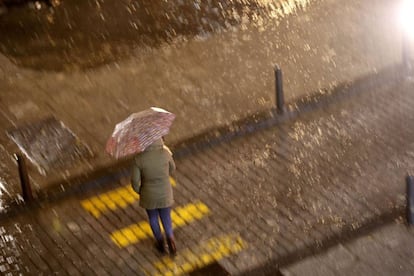 Una mujer cruza la calle esta noche bajo una intensa lluvia en Valencia