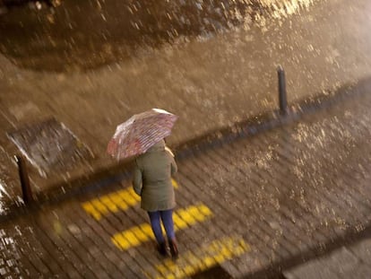 Una mujer cruza la calle esta noche bajo una intensa lluvia en Valencia